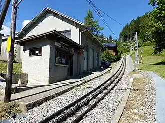 Vue générale de la gare de Crêt-d'y-Bau avec la voie, le quai et le bâtiment de la gare.