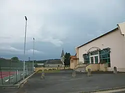 Le terrain de tennis, la salle des fêtes, en arrière-plan, le stade de football et l'église