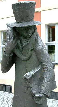 Sculpture intitulée Hoffmann et son chat, située devant le théâtre E.T.A. Hoffmann de Bamberg. Un personnage inquiétant en haut de forme et au visage indistinct tient sur son épaule droite un chat et porte un livre imposant sous son bras gauche.
