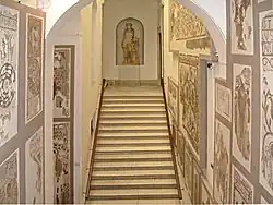 Perspective dans le département des mosaïques romaines vu de l'escalier d'accès avec des mosaïques au mur et une statue d'Apollon au fond.