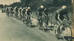 Photo en noir et blanc d'un peloton cycliste sur une route de campagne.