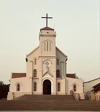 Plusieurs dizaines de personnes devant une église aux tons jaunes.