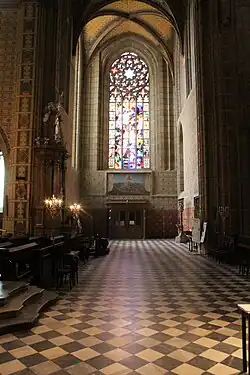 Photographie intérieure d'une église gothique se terminant par une rosace.
