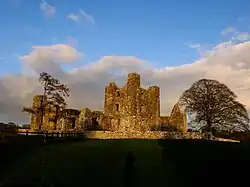 Photographie couleur d'un bâtiment en pierres largement ruiné.