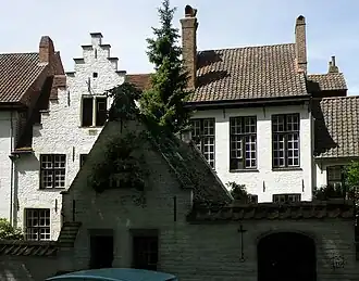 Les maisons no&nbsp;10 (à droite, début XIXe&nbsp;siècle) et no&nbsp;12 (à gauche, au pignon à gradins, XVIIe&nbsp;siècle). À l’avant-plan, apparaissant sombre sur la photo car à l’ombre des peupliers, le pigeonnier.