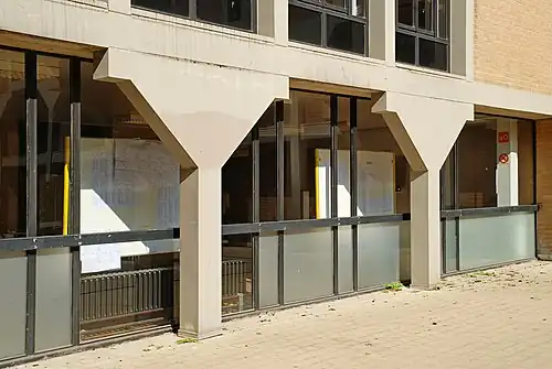 Colonnes de béton blanc soutenant la galerie.