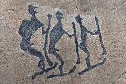 Pétroglyphes de trois personnes sur une roche.