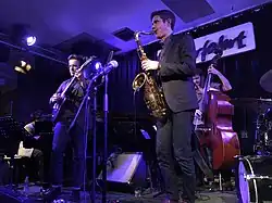 sur scène, Ben Wendel au saxophone au premier plan, Gilad Hekselman à la guitare à côté de lui. On voit un batteur et un pianiste en fond.