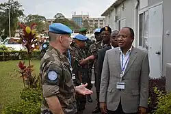 Des hommes politiques en costume discutent avec des soldats à béret bleu.