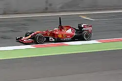 Photographie d'une monoplace de Formule 1 rouge, vue de profil, sur une piste sèche.