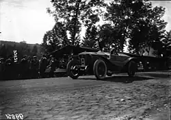 Photo d'une voiture en course avec, hors de la piste, des spectateurs.
