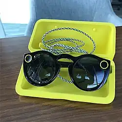 Première génération des Spectacles noire dans son coffret de charge jaune