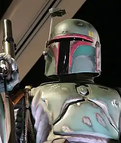 Homme portant un casque et un costume vert avec une arme.