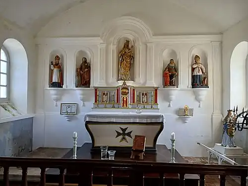 Autel marqué de la croix de Malte surmonté de cinq statues placées dans des niches.
