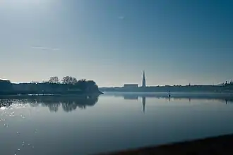 Photographie large de la Garonne avec un grand ciel bleu. On aperçoit la ville en fond.