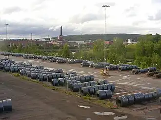 photo d'un parc à bobines. En arrière plan, l'usine