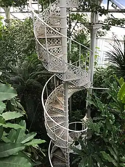 Un étroit escalier en spirale en fer forgé, très ajouré, monte vers le sommet de la serre.