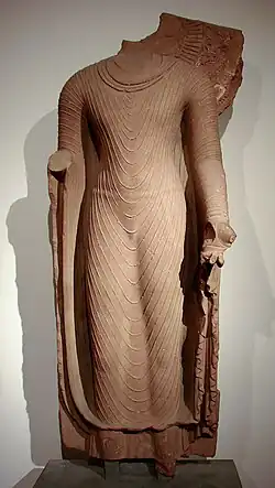 Bouddha en robe uttarâsangâ, début du VIe&nbsp;siècle empire Gupta, école de Mathura, grès rose, H. 142&nbsp;cm. Inde.