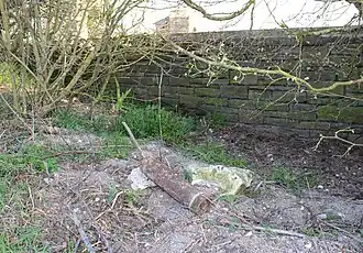 Obus non explosé derrière le mur du cimetière (photo prise le 21/03/2022).