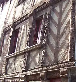 Photographie de la Maison des Marmousets, avec vue rapprochée des pans de bois et des statuettes (marmousets)