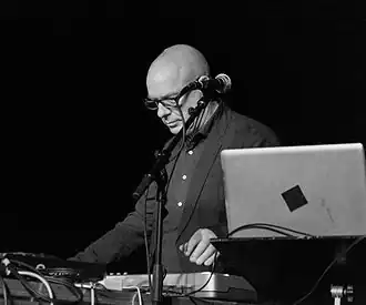 Portrait en noir et blanc de Brian Eno sur scène comme DJ en 2012.