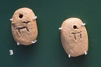 Deux petites tablettes d'argile avec des pictogrammes représentant des animaux et un signe rond.