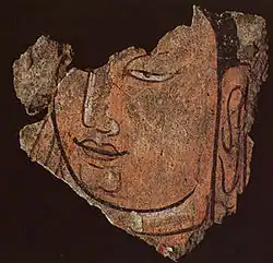 Détail d'une tête du Bouddha 21B. Registre haut du sanctuaire B en bois et enduits peints, vallée de la Keriya. Début du IIIe siècle. Musée provincial, Ürümqi.