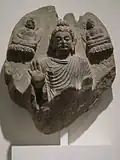 Le grand miracle de Sravasti (?). Buddha faisant le geste d'absence de crainte. Schiste, IIe – IIIe&nbsp;siècle. Monastère de Shotorak, région du Kapisa, Afghanistan. Musée Guimet