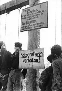 Des partisans soviétiques pendus. Le texte en allemand proclame « Nous sommes des bandits. Non seulement nous avons tué des soldats allemands, mais nous avons aussi tué et pillé des citoyens russes. » Un panneau indique « Interdiction de photographier ! »  (Russie, janvier 1943).