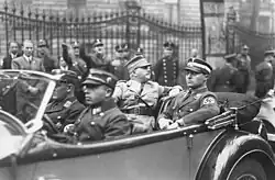 Photogphie en noir et blanc de Rhöm, assis sur le siège arrière d'une voiture, à côté de Karl Ernst