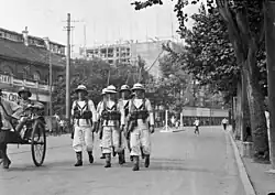Dans une artère de Bombay en 1932, marins britanniques patrouillant en armes pour assurer l’ordre public.