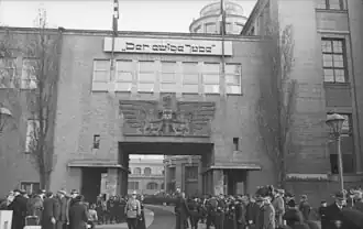 Photographie en noir et blanc de groupes de visiteurs devant l'entrée de l'exposition.
