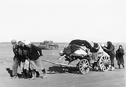 Photo en noir et blanc d'un petit groupe de personnes tirant une charrette.