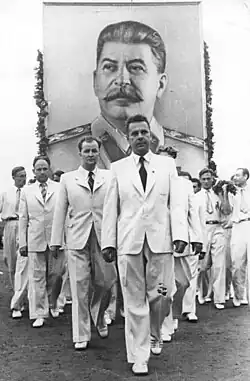 Photo noir et blanc d'hommes en costume blanc portant un portrait de Staline.