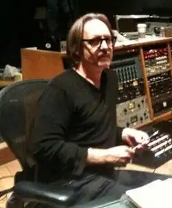 Photo de Butch Vig, le producteur de l'album, assis dans un fauteuil devant du matériel d'enregistrement.