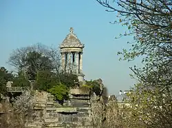 Photographie en couleurs d'un temple de gréco-romain entouré d'arbres, situé au niveau d'un belvédère, au sommet d'une falaise.