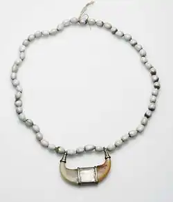 Collier de perles blanches avec un pendentif formé de deux griffes de tigre