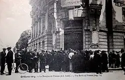 Carte postale noir et blanc montrant une file d'attente devant la Banque de France d'Orléans, le 2 août 1914.
