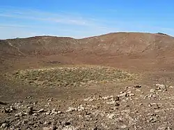 Vue du cratère avec un îlot de végétation arbustive épineuse.