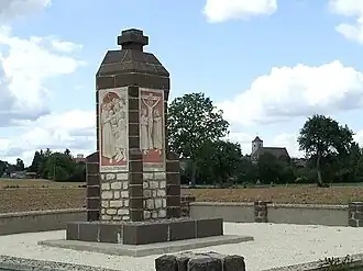 Le monument de la Vierge Marie. En arrière-plan à droite, l'église du village.