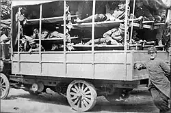 Vue de côté d'un camion équipé de civières où sont allongés des blessés en uniforme.