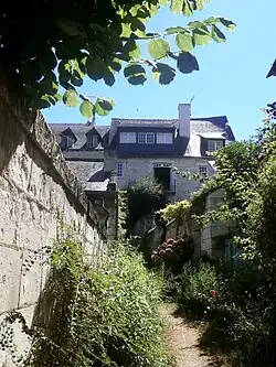 Photographie en couleurs d'une maison à étages au fond d'une ruelle.