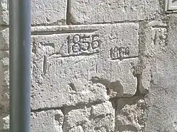 Photographie en couleur d'un pierre de taille gravée avec des repères et des dates.