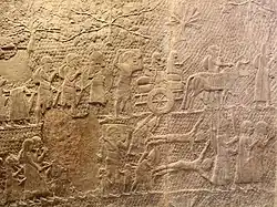 Après la prise de la ville : des troupes assyriennes conduisent des déportés emmenant leurs propres biens et animaux en exil, et d'autres soldats exécutent des vaincus en les écorchant vifs.