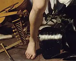 détail d'une peinture avec un pied nu posé au sol, autour duquel sont disposés divers objets