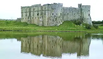 Photo d'un bâtiment imposant aux murs épais se reflétant dans un plan d'eau