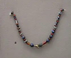 Collier en perles de cornaline et lapis lazuli, amulette en or en forme de mouche, provenant des tombes royales d'Ur. British Museum.
