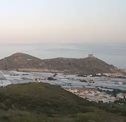 Vue sud-est depuis l'A-7 : El Romeral&nbsp;(es), la mer de serres, le château de Castell de Ferro&nbsp;(es) et la mer d'Alboran au-delà.