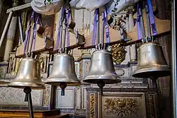 photographie en couleur montrant quatre petites cloches neuves et brillantes exposées devant un autel.