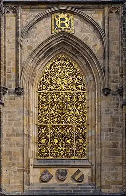 Une fenêtre, dans un ensemble de pierre de taille, constituée d'un important décor d'or.